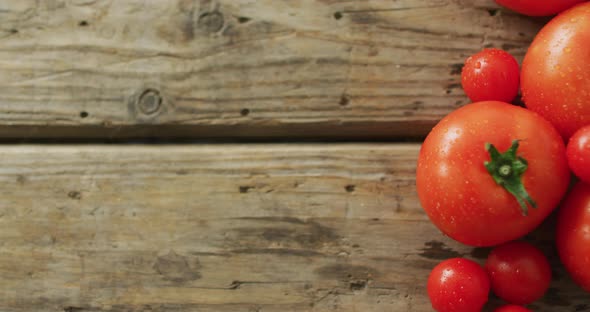 Video of fresh tomatoes and cherry tomatoes with copy space over wooden background