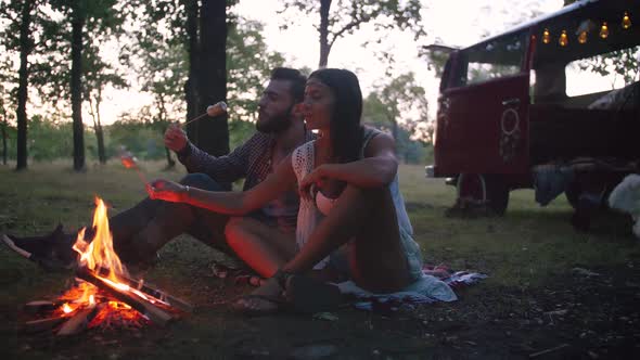 Beautiful Young Mixed Race Couple Roasting Marshmallows Over a Campfire While Enjoying Their Road