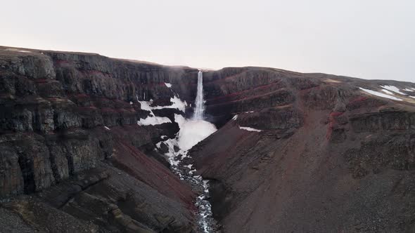 Big waterfall Hengifoss surrounded by red layers of clay