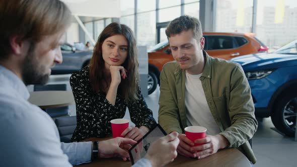 A Dealership Manager Tells a Young Couple About New Cars