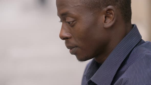 Pensive depressed young african man in the street- profile