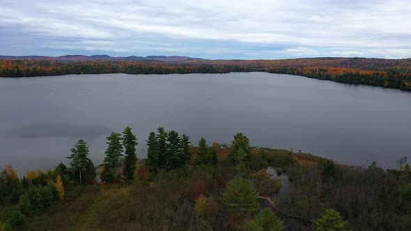 Aerial Flyover of stream entering a pond in northern maine in autumn