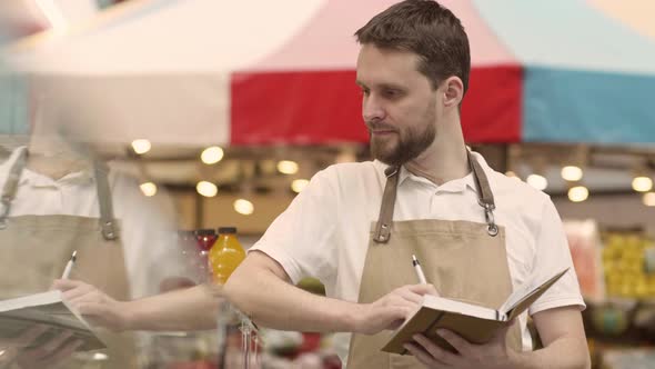 Male Grocery Shop Seller Making Notes in Notepad