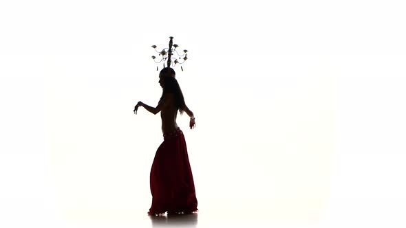 Attractive Belly Dancer Woman Dancing with Candles on Her Head and Shaking Her Hips, Silhouette, on