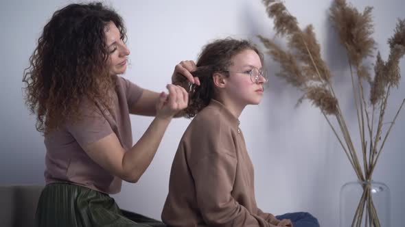 Lovely Curlyhaired Woman Weaves Her Teenage Hair's Pigtails