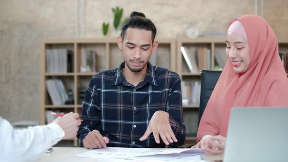 Two young Islamic colleagues work in a small startup office.