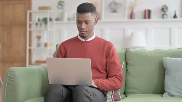 African Man Working on Laptop on Sofa