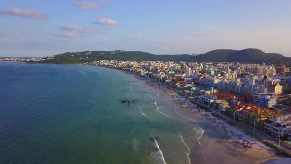 Aerial wide shot of Bombas beach crowded with tourists at golden hour, Brazil
