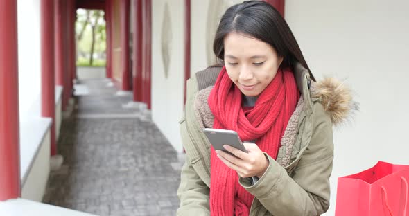 Woman looking at mobile phone in chinese garden