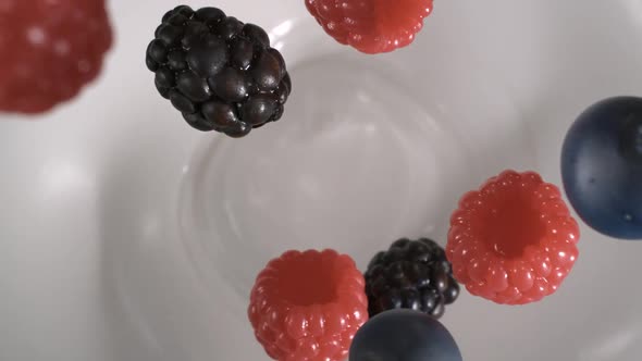 Fresh red and black raspberries rain on yogurt in slow motion - High-angle shot