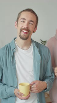 A Handsome Man in a Blue Shirt is Standing Near His Best Friend Looking at the Camera and Smiling