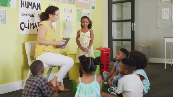 Video of happy caucasian female teacher and class of diverse pupils studying ecology in classroom alt