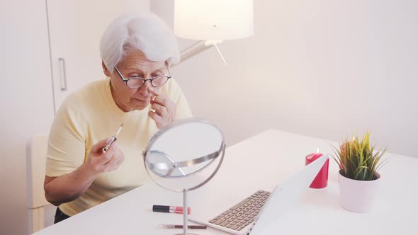 Elderly Woman Applying Make Up in the Office