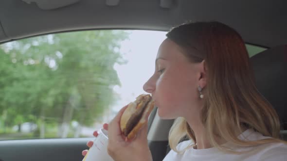 Hungry Woman Eating Burger Sitting in Car, Junk Food