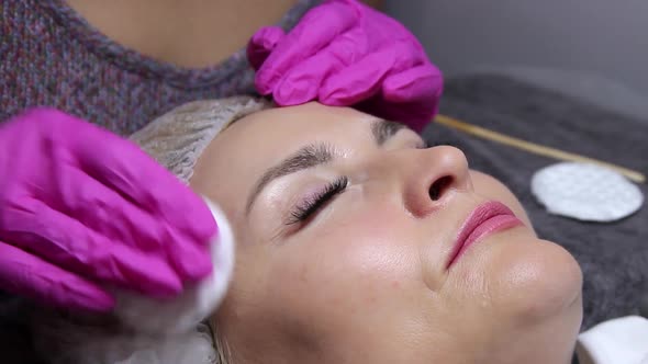 the master wipes the model's eyebrows with a cotton swab. eyebrow trim