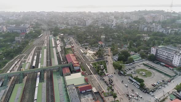 City landscape with train station, streets, park and buildings around under a dusty sky