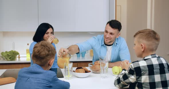 Friendly Family Sitting Around Kitchen Table and Having Breakfast in the Morning