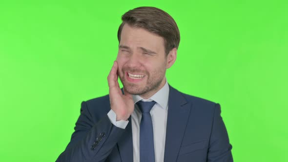 Young Businessman having Toothache on Green Background