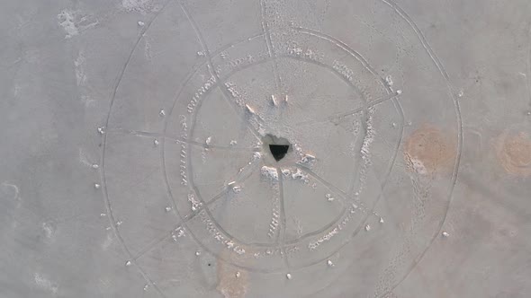 Triangle shaped ice hole on frozen lake. Aerial top-down rising and circling