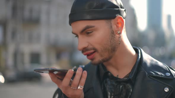 Closeup Side View Cheerful Gay Man Talking on Speakerphone Laughing Standing in Urban City