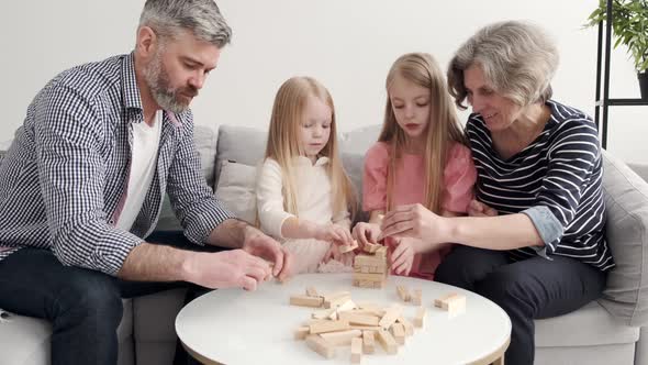 Grandparents Play Tower Game with Two Girls