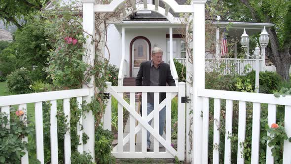 Elderly man walking through gate in his yard