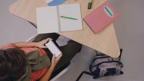 Boy is Actively Playing Mobile Games Sitting at the Desk in School