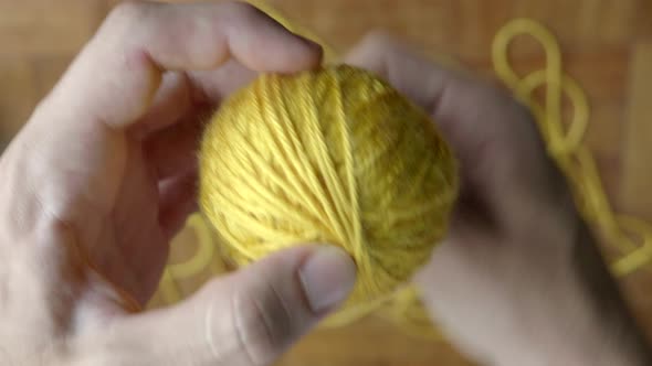 Hand winding ball of yellow wool. Static. Blur background. Top view