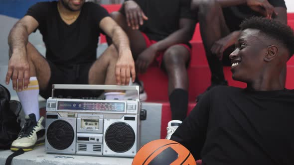 Young multiracial people having fun listening music with vintage boombox outdoor