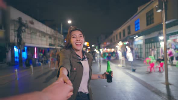 Portrait of Asian woman traveler hold boyfriend's hand, walk on street.