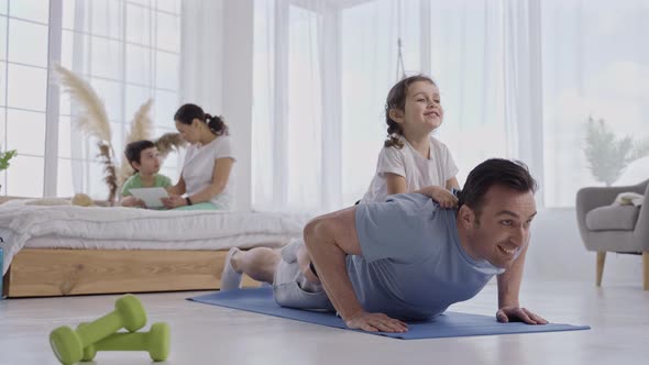 Active Father Doing Push Ups with Daughter on Back