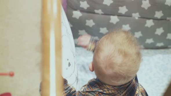 Baby Plays in Rocking Soft Cot with Star Blanket in Room