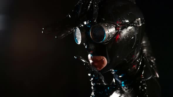 Closeup of a Head in a Black Latex Helmet Glasses and Drops of White Liquid