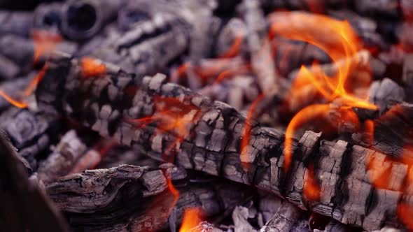 Coals are burning in the fire. Smoldered logs with slight flame background. 