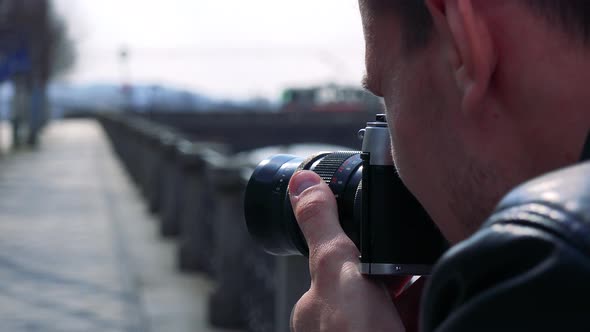 A Young Man Takes Photos of a Street in an Urban Area with a Camera - Closeup
