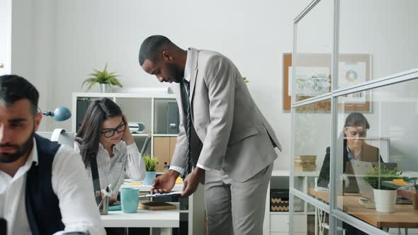 AfroAmerican Man Talking to Asian Colleague Then Dancing Having Fun in Office