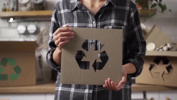 Processing Of Raw Materials Of Products. Girl Holding A Recycling Sign Stands Against The Background