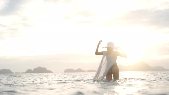 Woman In Thong Walking In Sea As Sun Sets