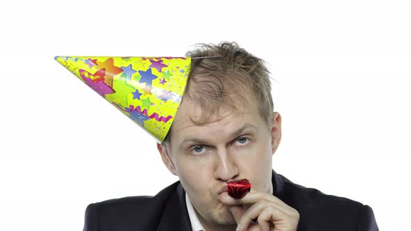 Drunk Sleepy Young Businessman in Festive Cap Blowing a Whistle. Hangover