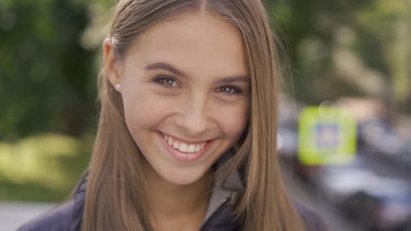 Close-up of Attractive Young Caucasian Woman with Long Brown Hair Smiling Happily Looking at Camera