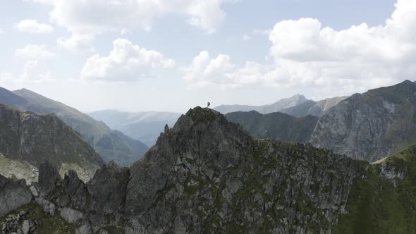 Man Standing on top of a Cliff in Rocky Mountains