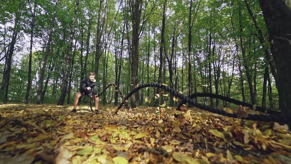 Training with battle ropes in the forest in autumn. 