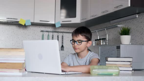 Boy with Textbooks Doing Homework at School Using a Laptop at Home. Online Learning, Distance