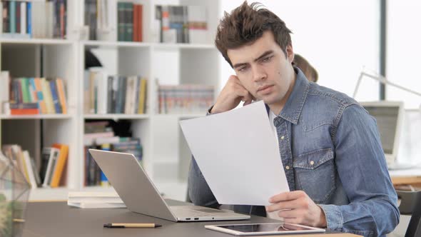 Pensive Creative Man Reading Documents at Work