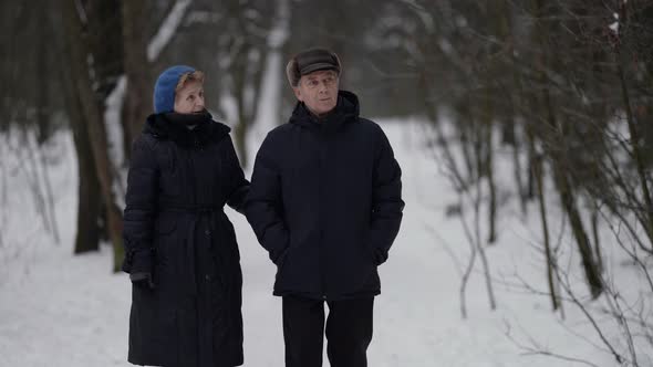 An Elderly Couple Walking in the Woods During the Day in Winter Dressed in Warm Comfortable Clothes