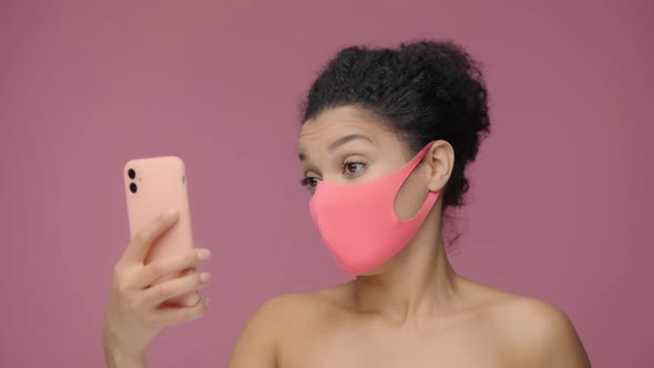 Beauty Portrait of Young African American Woman in Pink Protective Mask Taking Selfie Using