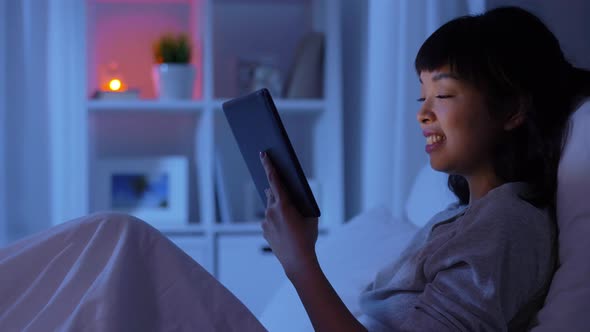 Woman with Tablet Pc in Bed at Home at Night