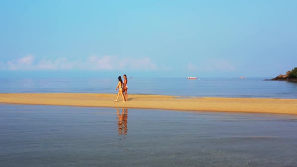 Beautiful ladies relaxing on perfect island beach lifestyle by turquoise water with bright sand back