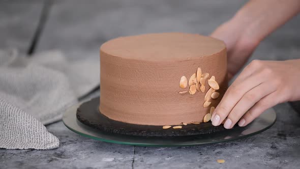 Female Pastry Chef Prepares a Cake and Decorates It with Almond Flakes