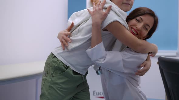 Live Camera Zoom in to Joyful Caucasian Pediatrician and Patient Hugging in Hospital Smiling